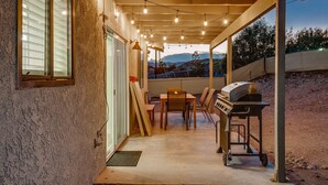 Ein überdachter Patio-Bereich mit Grill, Tisch und Stühlen sowie einer Satellitenschüssel.