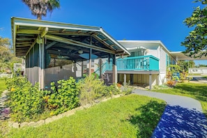 A residential house with a covered porch, a fenced yard, and a clear blue sky.