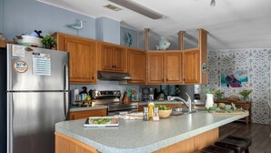 Una cocina moderna con armarios de madera, un refrigerador de acero inoxidable, una isla grande con taburetes y diversos electrodomésticos.