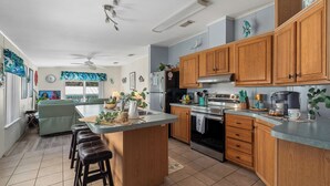 Una cocina moderna con armarios de madera, una isla central y una zona de comedor con un sofá verde.