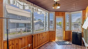 A room with wooden walls, large windows, a ceiling fan, and a black refrigerator. - Rustic Riverside Charm and Exclusive Fishing Access! (Richland)