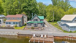 A lakeside property with a dock, a small boat, and several cabins with green roofs. - Rustic Riverside Charm and Exclusive Fishing Access! (Richland)