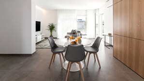 Un salon moderne avec un coin repas, comprenant une table ronde avec des chaises, un canapé et un téléviseur.