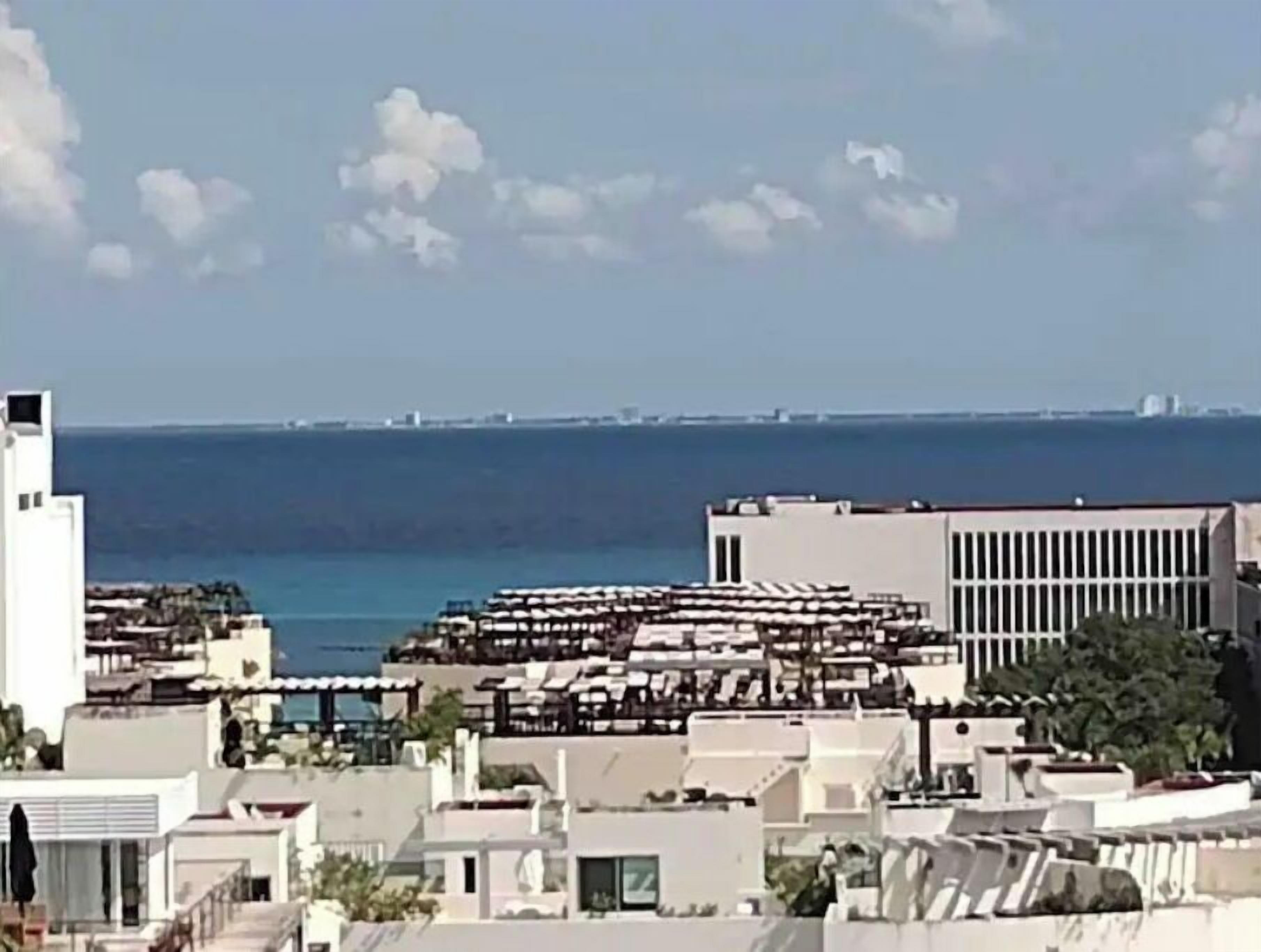 A coastal cityscape with modern buildings, a marina, and a clear view of the sea.
