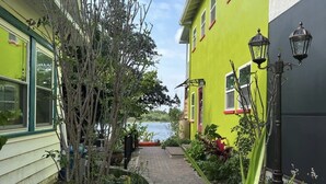 Un estrecho sendero de ladrillo entre dos edificios, uno con una puerta verde y otro con una pared verde.