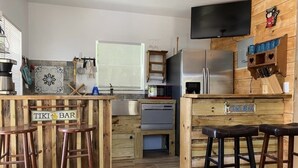 Una cocina con taburetes de madera, un refrigerador, un microondas y una cafetera.