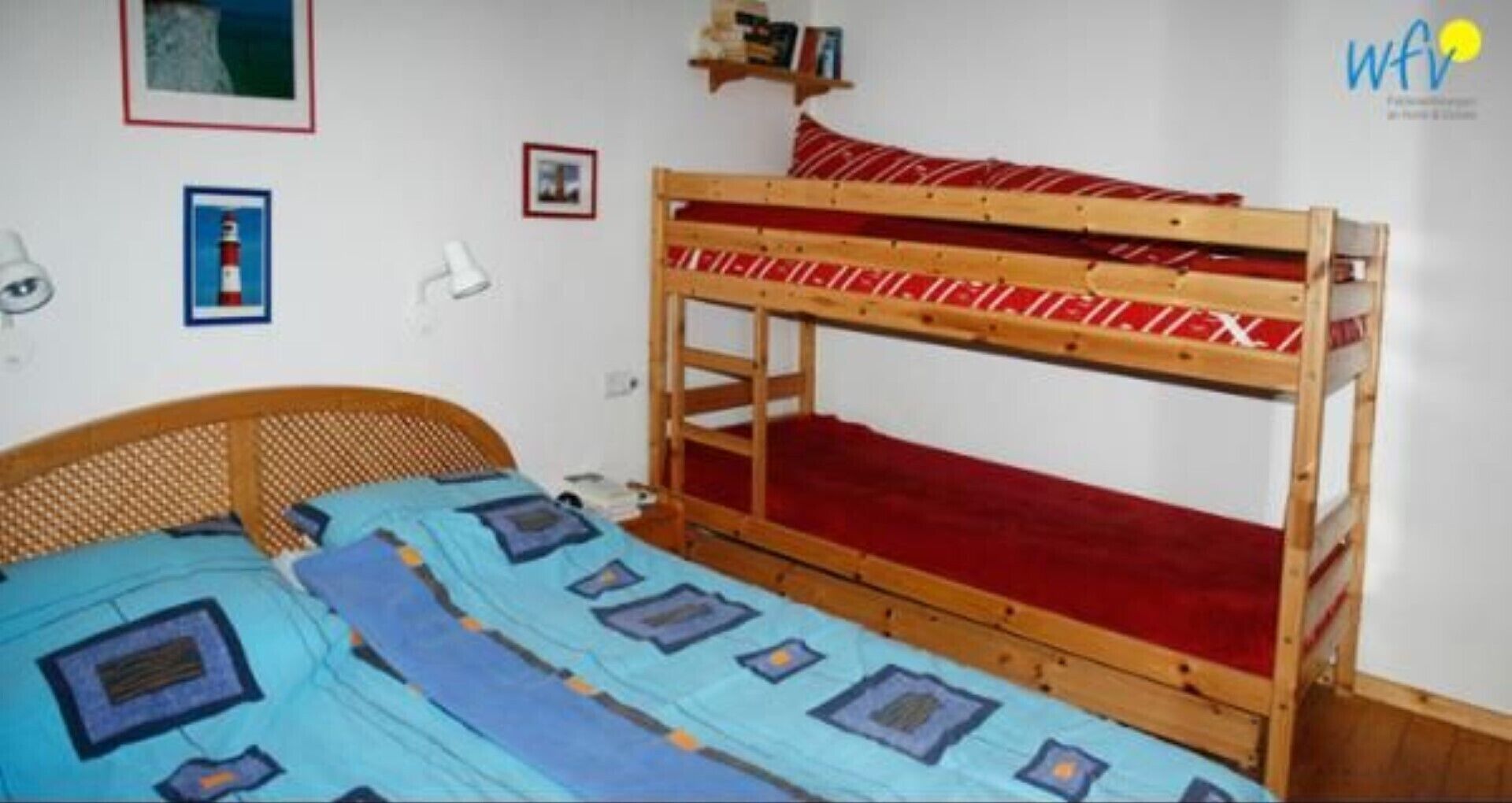 A bunk bed room with a wooden headboard, a red mattress, and a blue bedspread.