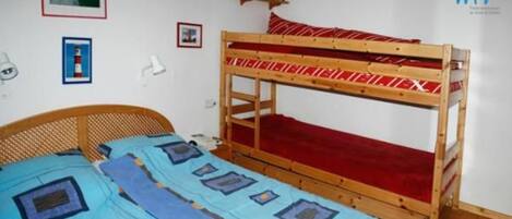 A bunk bed room with a wooden headboard, a red mattress, and a blue bedspread.