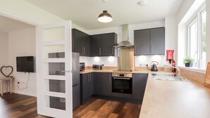 Una cocina moderna con armarios oscuros, horno empotrado, microondas y un amplio ventanal que proporciona luz natural.