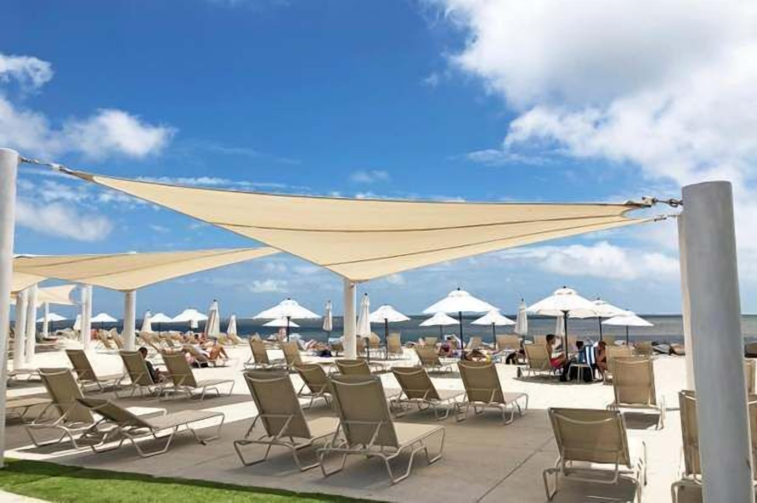 A beachside lounge area with sun loungers and umbrellas, overlooking the ocean.