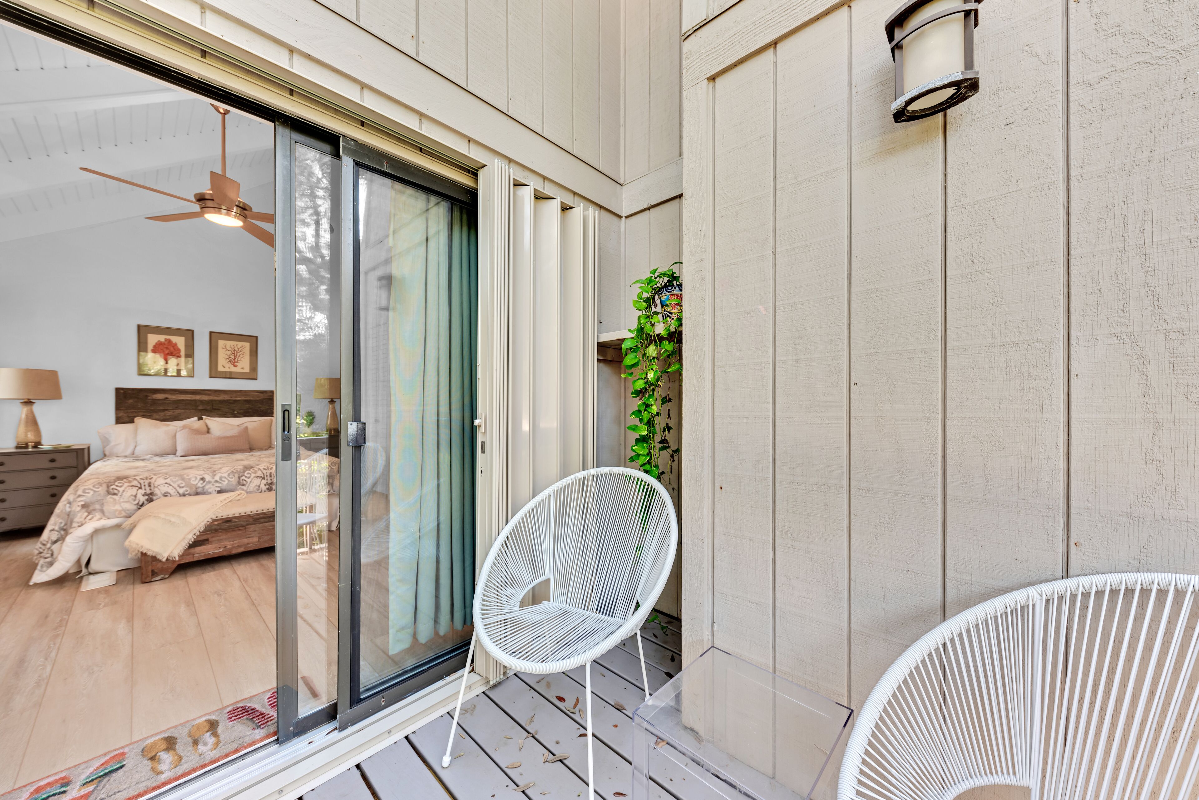 A bedroom with a bed, a sliding glass door leading to a balcony, and a white chair.