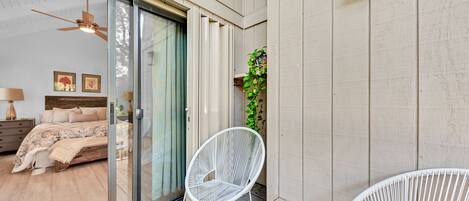 A bedroom with a bed, a sliding glass door leading to a balcony, and a white chair.
