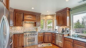 A kitchen with wooden cabinets, stainless steel appliances, and a window providing a view of the outdoors. - Wine Country Gateway w/ Views Btwn Napa & SF (Vallejo)