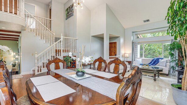 A spacious dining area with a large wooden table, white chairs, and a staircase leading to an upper level. - Wine Country Gateway w/ Views Btwn Napa & SF (Vallejo)