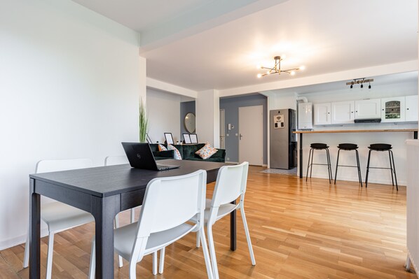 A modern kitchen with white cabinets, a black countertop, and a laptop on the table.