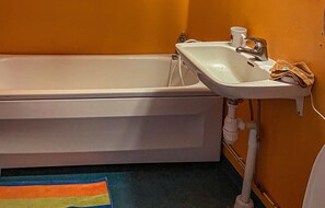 A bathroom with a bathtub, a sink, and a towel rack.