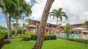 Ein Hotel mit Pool, Palmen und einem gepflegten Garten.