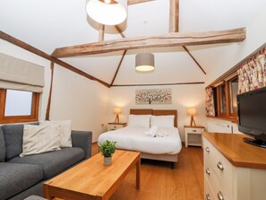 Une chambre confortable avec un lit, des lampes de chevet, une télévision, un canapé et une table basse en bois.