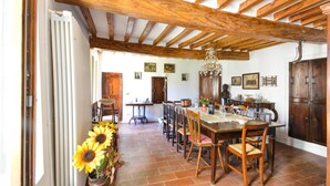 A rustic dining room with a wooden ceiling, a large dining table surrounded by chairs, and a radiator on the wall. - Pet friendly home in Monchio delle Olle (Monchio delle Olle)