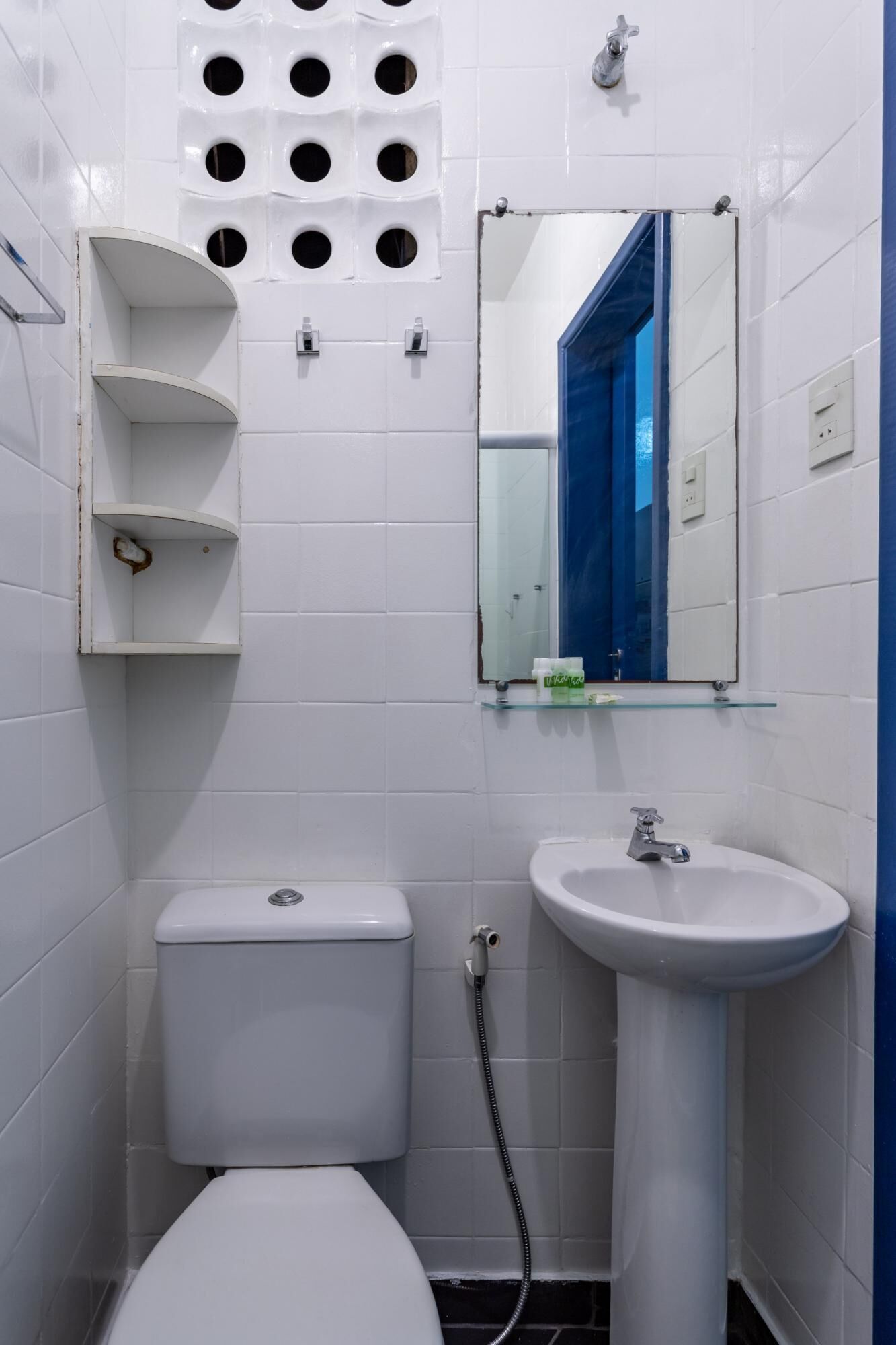 Un baño pequeño y limpio con azulejos blancos, un inodoro, un lavabo y un espejo.