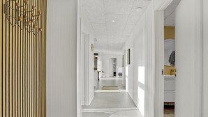 A modern hallway with a wooden slat wall on the left, leading to a room with a white door and a small table. - Cozy home in Tarm with WiFi (Tarm)