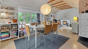 Un vaste espace dédié à la salle à manger, comprenant une grande table, des chaises et un luminaire suspendu.
