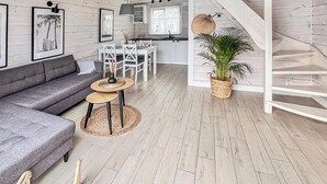 A modern living room with a grey sofa, a small round table with a lamp, and a staircase leading to an upper level. - Stunning home in Mielno (Mielno)