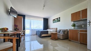 A modern living room with a bed, sofa, and dining area. There is a TV mounted on the wall and a window with curtains. - Nice home in Slowienkowo with WiFi (Slowienkowo)