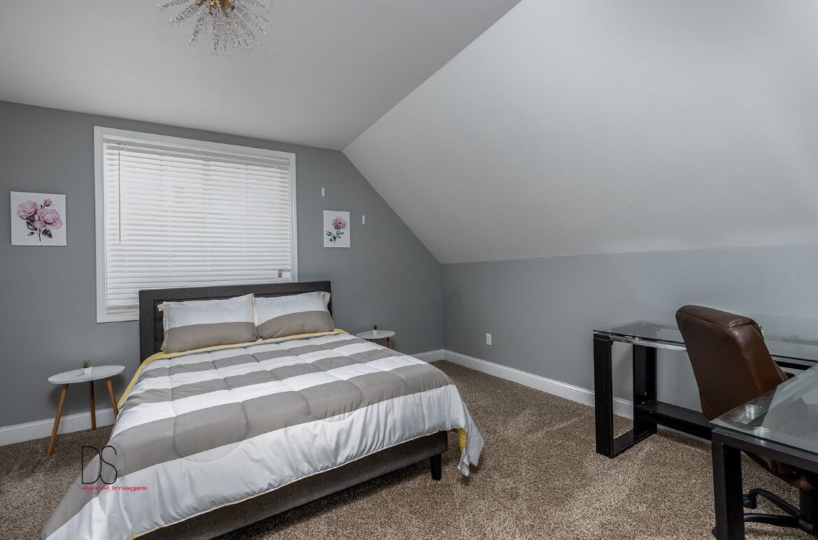 A bedroom with a bed, a desk, and a chair.