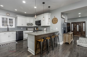 A modern kitchen with white cabinets, a granite countertop, and a central island with bar stools.