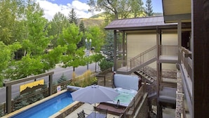 Un patio trasero con piscina, jacuzzi y mobiliario para exterior.