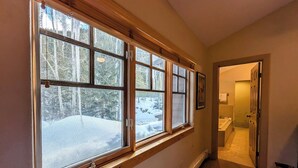 A hallway with large windows, a door leading to a bathroom, and a view of a snowy landscape. - Starfire 1994 (Keystone)