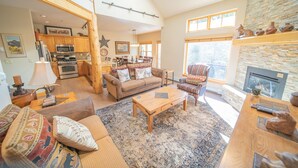 A spacious living room with a high ceiling, a fireplace, and a kitchen in the background. - Starfire 1994 (Keystone)