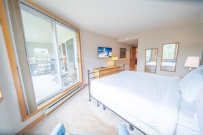 A bedroom with a large bed, a dresser, a window with a view, and a painting on the wall. - Pines 2089 (Keystone)