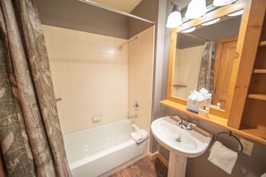 A bathroom with a bathtub, a sink, and a mirror. - Expedition Station 8593 (Keystone)