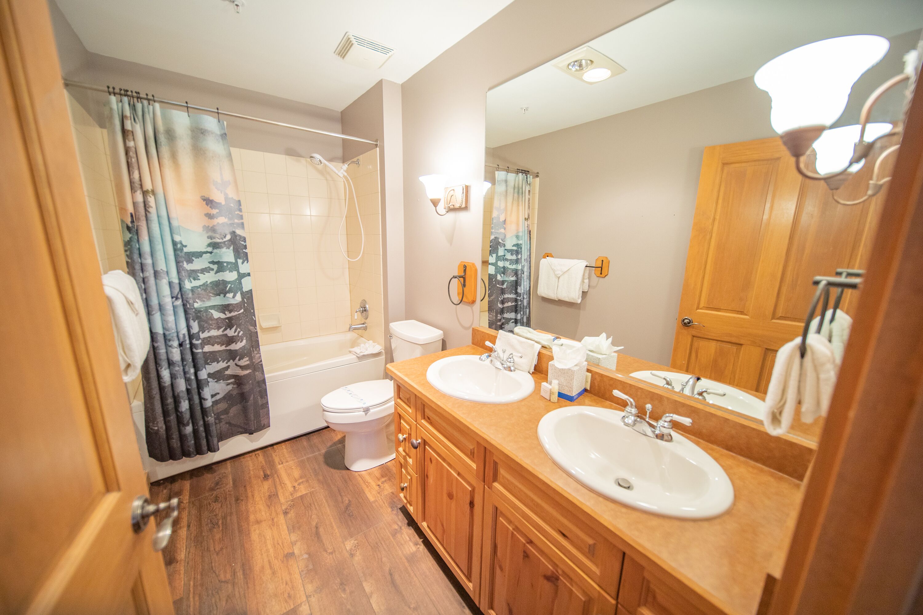 A bathroom with a shower, toilet, and two sinks.
