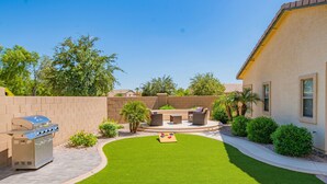 A backyard with a barbecue grill, outdoor seating, and a well-maintained lawn. - Gorgeous & Comfy Family Getaway ~ Games ~ Backyard (Surprise)