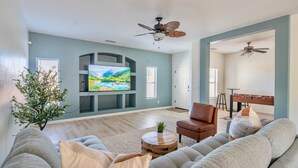 A living room with a large flat-screen TV, a brown leather chair, a grey sofa, and a wooden coffee table. - Gorgeous & Comfy Family Getaway ~ Games ~ Backyard (Surprise)