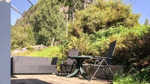 An outdoor seating area with a table and chairs, surrounded by dense greenery and trees. - 1 bedroom stunning home in Tonstad (Tonstad)