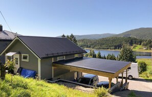 A two-story house with a large deck and a covered carport.