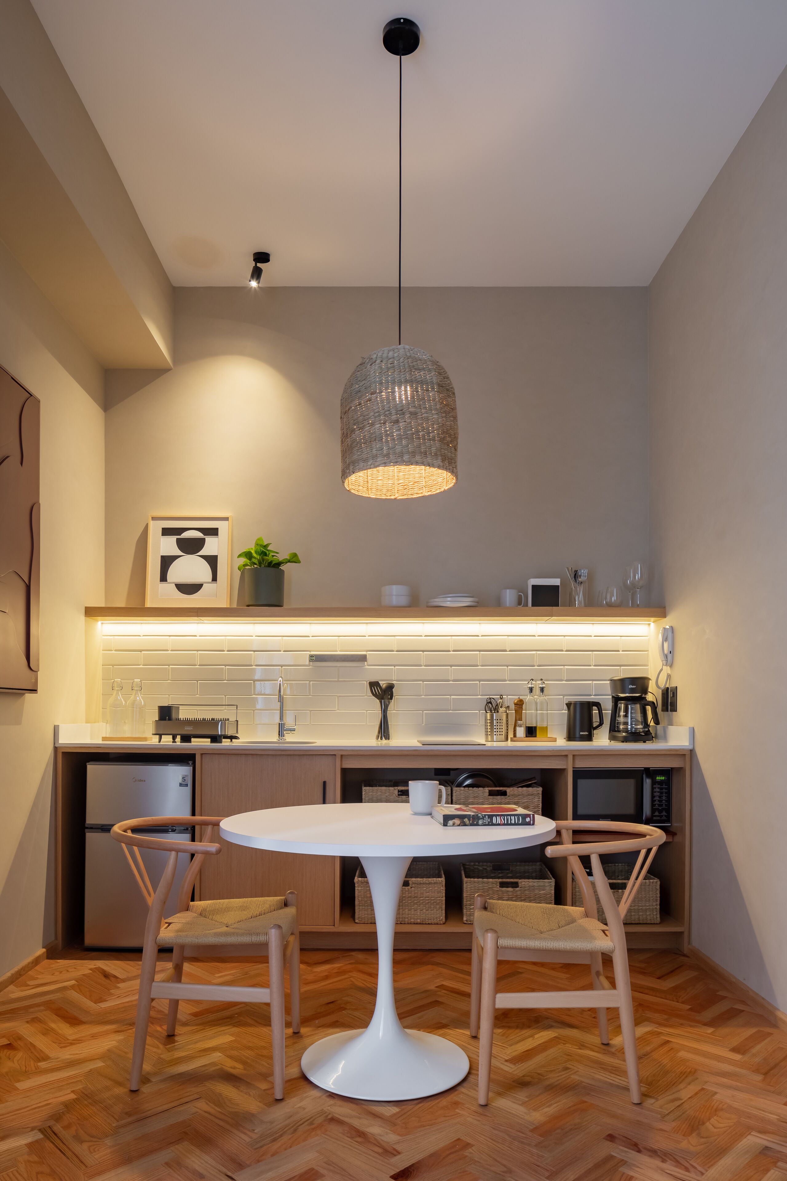 Una cocina moderna con una mesa redonda de comedor, dos sillas, una lámpara colgante y un horno empotrado.