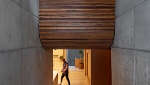 Et moderne interiør med loft af trælameller, betonvægge og trægulv.