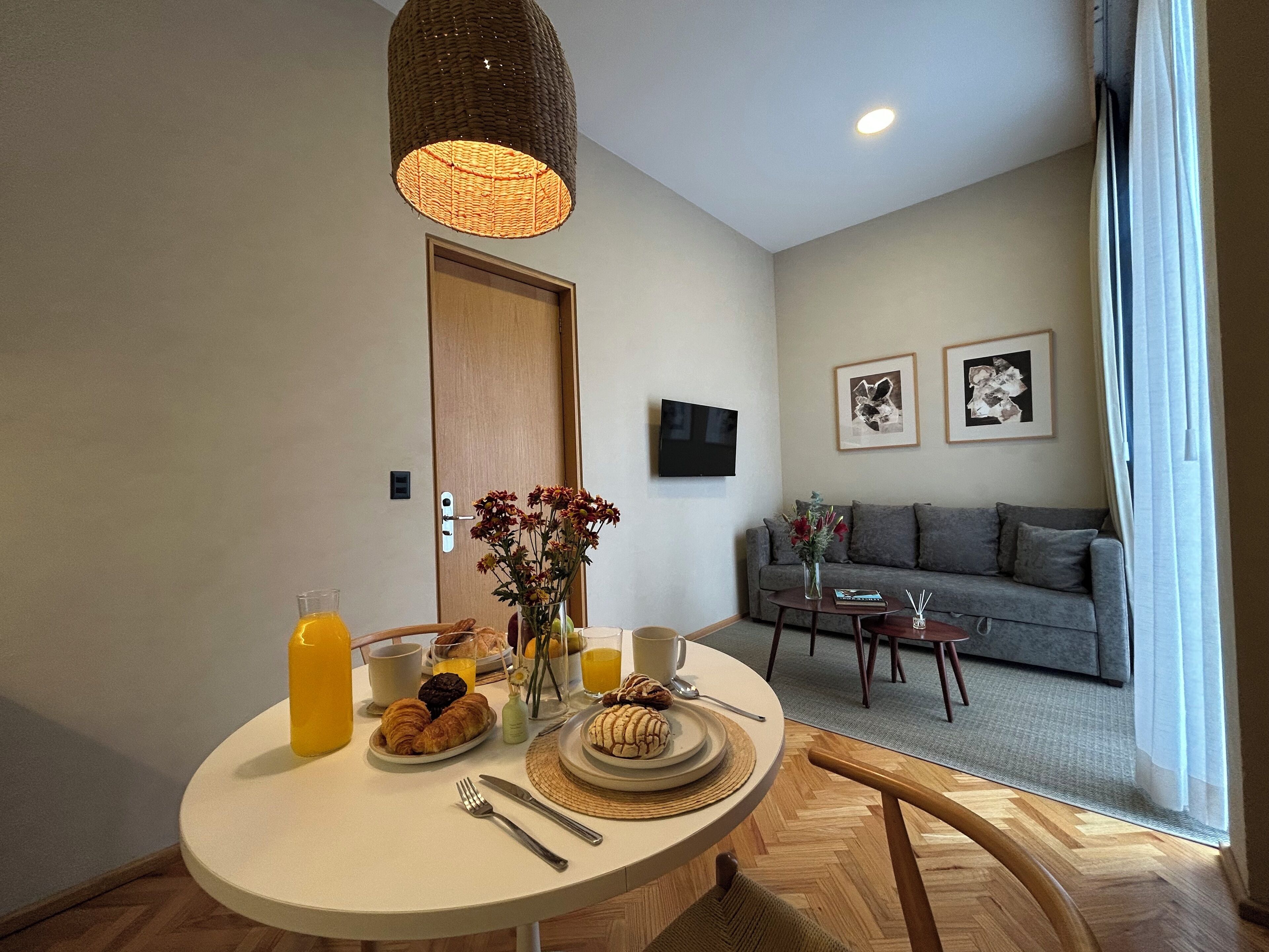 Un comedor con una mesa redonda, productos para el desayuno y una lámpara colgante.