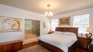 A bedroom with a large bed, a wooden dresser, a nightstand, and a chandelier. - Beautiful Spanish Style Home In The Heart of Coral Gables (Coral Gables)