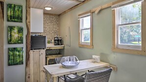 Una cocina compacta con una mesa de madera, sillas, microondas y cafetera.