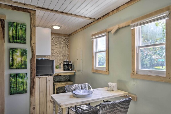 A compact kitchen with a microwave, coffee maker, and a small dining area with a table and chairs.