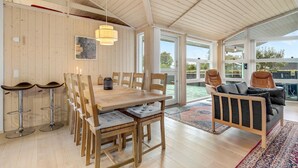 Una habitación amplia con una mesa de comedor de madera, sillas, un sofá y un ventanal que ofrece vistas a una piscina.