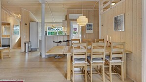 Interior de madera con comedor, cocina y vistas al exterior.