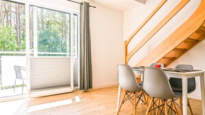 Een moderne eethoek met een tafel en stoelen, een schuifdeur naar een balkon en een houten trap.