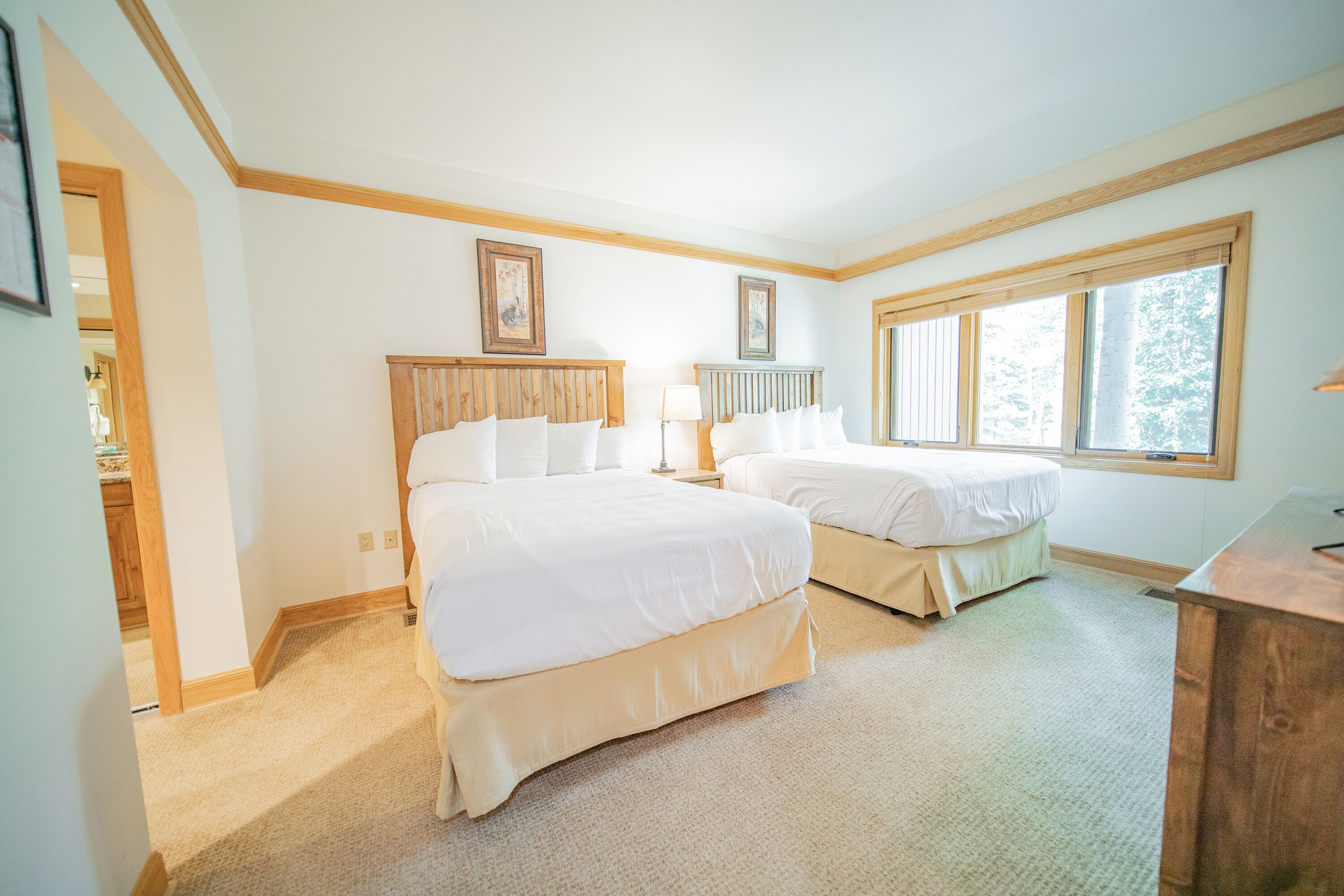 A bedroom with two beds, a wooden headboard, a window, and a desk.